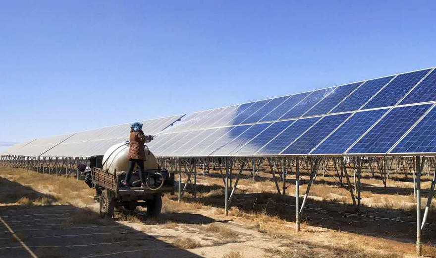 甘肅天水某光伏發(fā)電基地工人正在向被塵土覆蓋的太陽能光伏發(fā)電板噴灑清洗劑